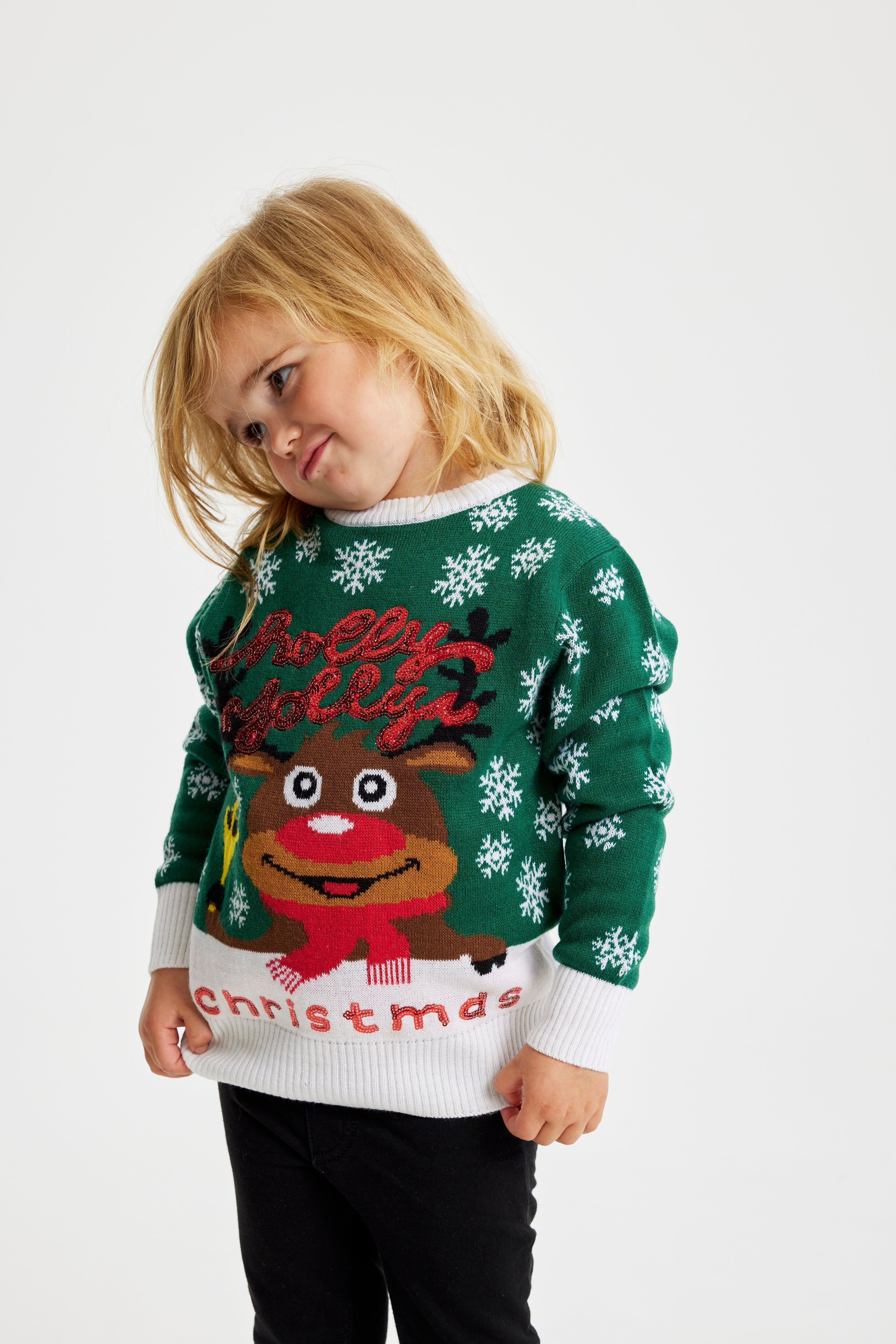 Un bambino che indossa un maglione natalizio verde.